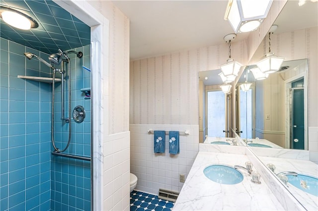 127 Mount Odin Dr, Hempfield Twp, PA 15601 - bathroom featuring wallpapered walls, a wainscoted wall, double vanity, tiled shower, and tile walls