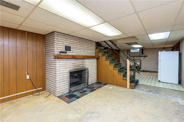 127 Mount Odin Dr, Hempfield Twp, PA 15601 - finished below grade area with freestanding refrigerator, a drop ceiling, stairway, a fireplace, and wood walls