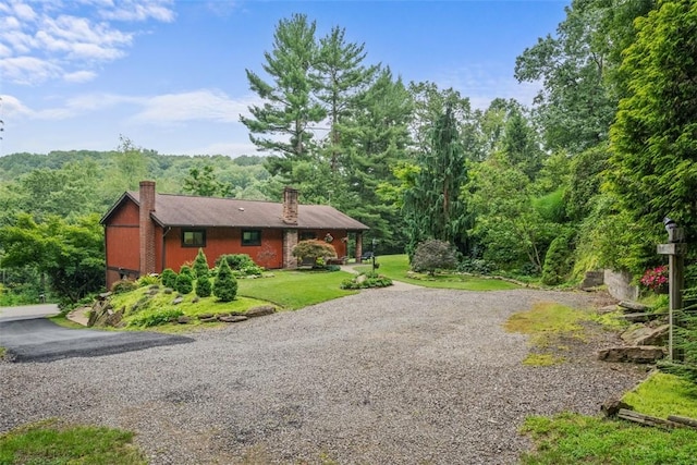 71 Mcclure Rd, West Deer, PA 15024 - view of side of home with a chimney, gravel driveway, a wooded view, and a yard