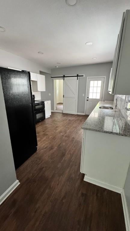 4010 Jane St, West Mifflin, PA 15122 - kitchen featuring range with electric stovetop, light stone countertops, a barn door, dark wood-style floors, and freestanding refrigerator