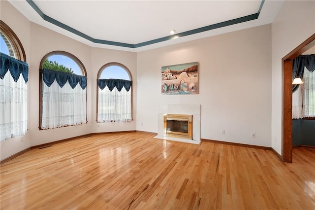 4 Hawthorne Ln, Penn Twp, PA 15642 - unfurnished living room featuring a tray ceiling, wood finished floors, and a fireplace with flush hearth