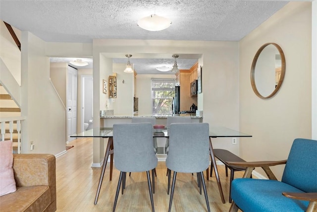 3269 Dawson St, Oakland, PA 15213 - dining room featuring light wood-type flooring, a textured ceiling, and stairway