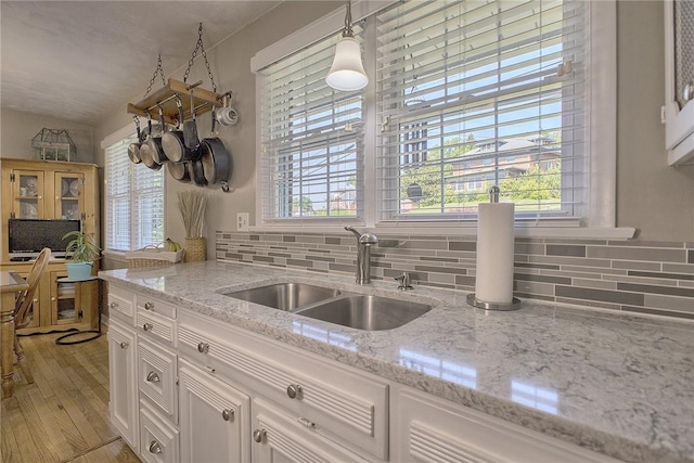 2 Redgrave Dr, Hempfield Twp, PA 15601 - kitchen featuring decorative backsplash, white cabinets, light wood finished floors, light stone counters, and decorative light fixtures