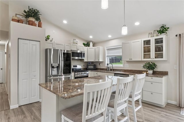 196 Weathervane Dr, Slippery Rock Twp, PA 16057 - kitchen featuring appliances with stainless steel finishes, light wood-style floors, a kitchen bar, glass insert cabinets, and white cabinetry