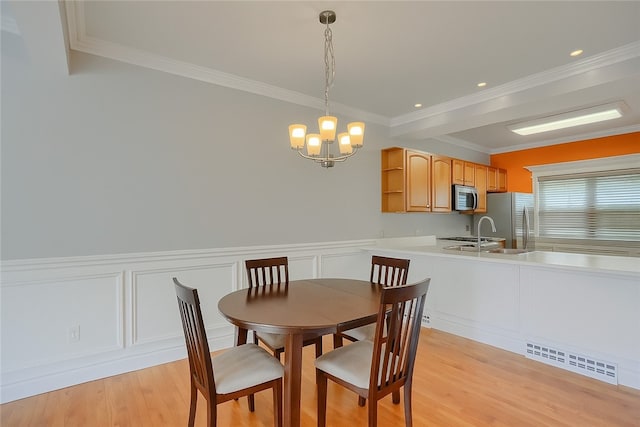 184 Wynne St, Shaler, PA 15209 - dining space featuring a chandelier, ornamental molding, light wood-type flooring, a decorative wall, and a wainscoted wall
