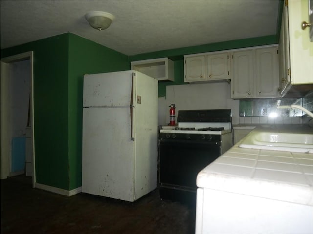 234 Simon Aly, Duquesne, PA 15110 - kitchen with gas stove, freestanding refrigerator, white cabinetry, decorative backsplash, and tile countertops