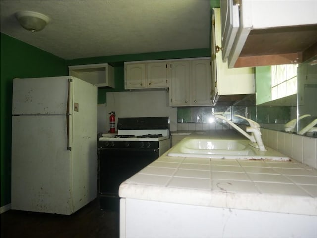 234 Simon Aly, Duquesne, PA 15110 - kitchen with tile countertops, range with gas cooktop, freestanding refrigerator, and white cabinetry