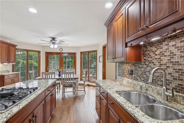 308 Heather Hill Dr, Pine Twp, PA 15044 - kitchen with stainless steel gas cooktop, a ceiling fan, decorative backsplash, hardwood / wood-style floors, and light stone counters