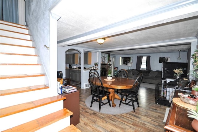 8263 Mentor Rd, Forward Twp, PA 15037 - dining room featuring stairway, wood finished floors, arched walkways, and beamed ceiling