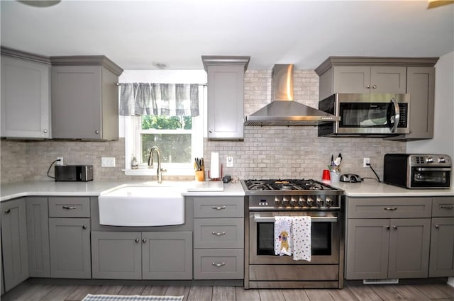 111 Wood St, Rostraver, PA 15089 - kitchen with appliances with stainless steel finishes, gray cabinetry, wall chimney range hood, and backsplash