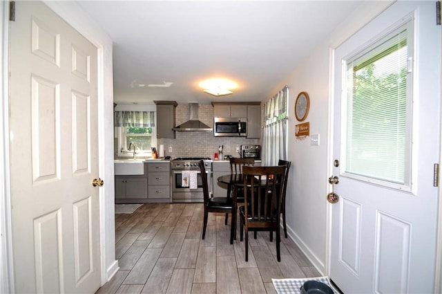 111 Wood St, Rostraver, PA 15089 - kitchen with stainless steel appliances, wall chimney exhaust hood, gray cabinets, light wood-style flooring, and decorative backsplash