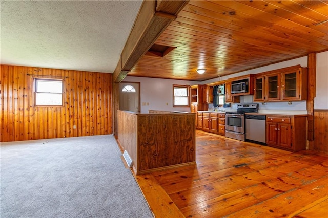 109 New Orchard Dr, Frazer, PA 15084 - kitchen with appliances with stainless steel finishes, brown cabinetry, plenty of natural light, wood walls, and glass insert cabinets