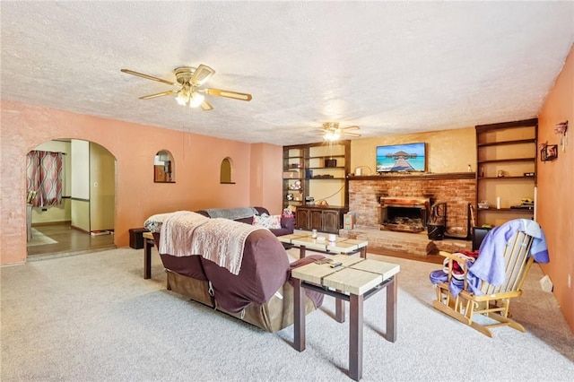 168 Debernardo Ln, Mahoning Twp, PA 16132 - living room featuring a ceiling fan, a textured ceiling, arched walkways, a fireplace, and carpet