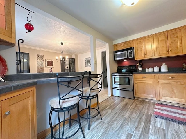 157 Aberdeen Dr, Mccandless, PA 15237 - kitchen featuring stainless steel appliances, dark countertops, ornamental molding, a breakfast bar, and light wood finished floors