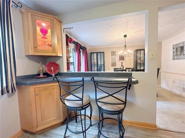 157 Aberdeen Dr, Mccandless, PA 15237 - kitchen with a kitchen bar, a chandelier, ornamental molding, light brown cabinetry, and tile counters