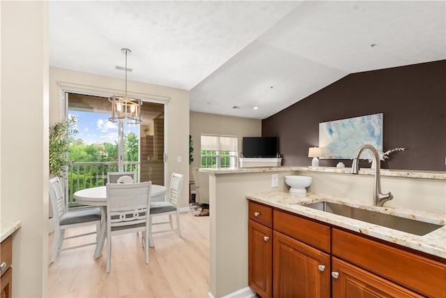 219 Stockton Rdg, Cranberry Twp, PA 16066 - kitchen featuring brown cabinetry, light stone counters, light wood-type flooring, lofted ceiling, and decorative light fixtures