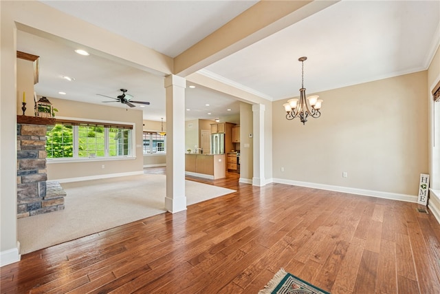 416 Willow Ct, Allegheny Twp, PA 15613 - unfurnished living room featuring ceiling fan, a chandelier, wood finished floors, decorative columns, and ornamental molding