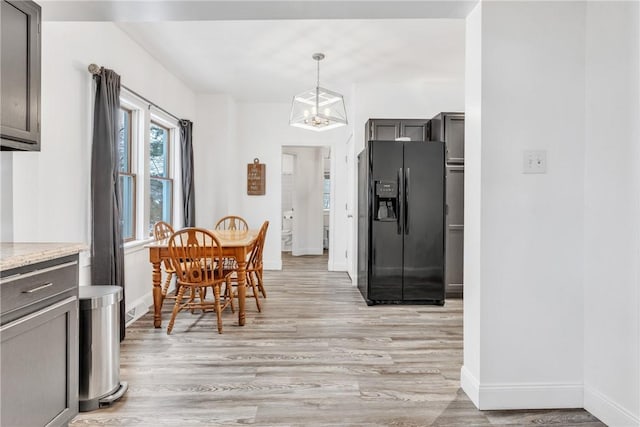 203 Stoney Hollow Rd, Winfield Twp, PA 16023 - kitchen featuring black fridge with ice dispenser, light wood-style flooring, a chandelier, hanging light fixtures, and light stone counters