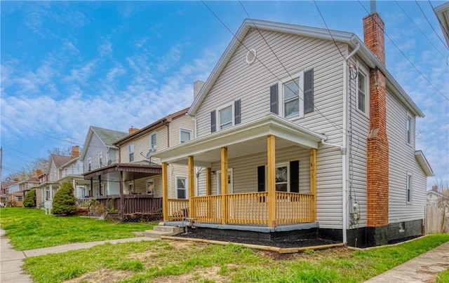 1122 Wade St, Aliquippa, PA 15001 - view of front of home with covered porch, a chimney, and a front lawn