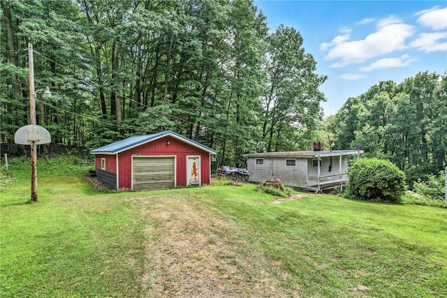 3067 N 3rd St, Jamestown, PA 16134 - view of green lawn featuring a garage, an outdoor structure, a wooded view, and driveway