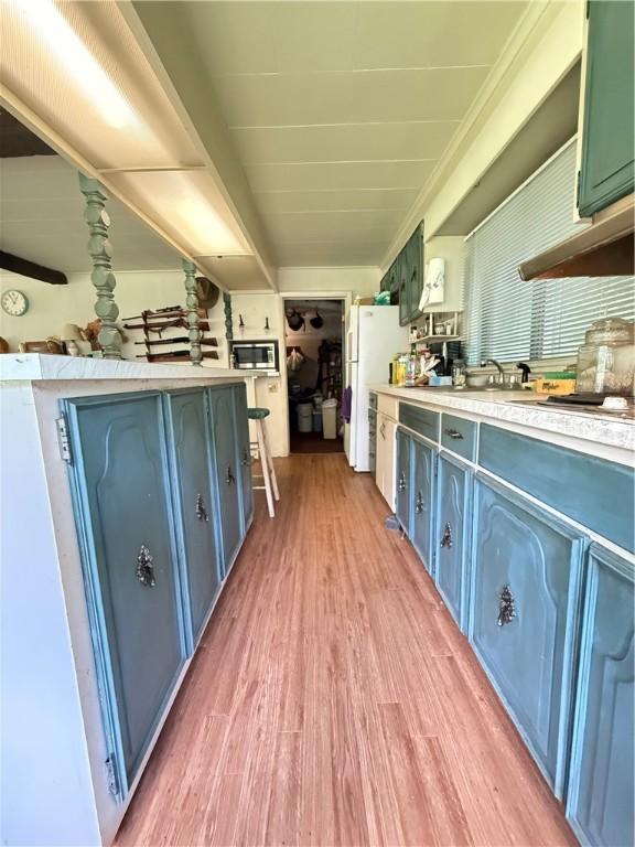 3067 N 3rd St, Jamestown, PA 16134 - kitchen featuring stainless steel microwave, light wood-style flooring, light countertops, freestanding refrigerator, and blue cabinetry