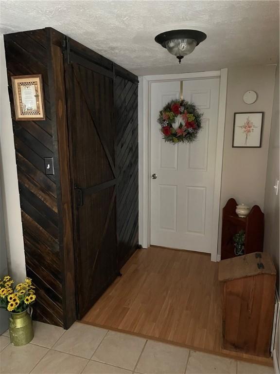 170 Laidleys Run Rd, West Finley, PA 15376 - foyer featuring a textured ceiling, light tile patterned flooring, a barn door, and wooden walls