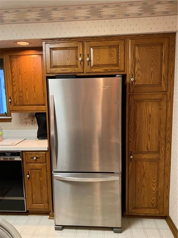 39 Hogue Rd, West Middlesex Boro, PA 16159 - kitchen with freestanding refrigerator, light floors, brown cabinetry, dishwasher, and wallpapered walls