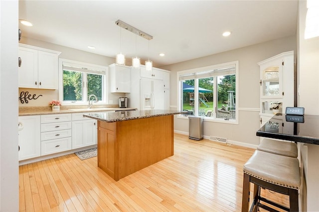 652 Cheyenne Trl, Jackson Twp, PA 16137 - kitchen with white cabinets, a center island, white refrigerator with ice dispenser, light wood-style flooring, and dark stone countertops