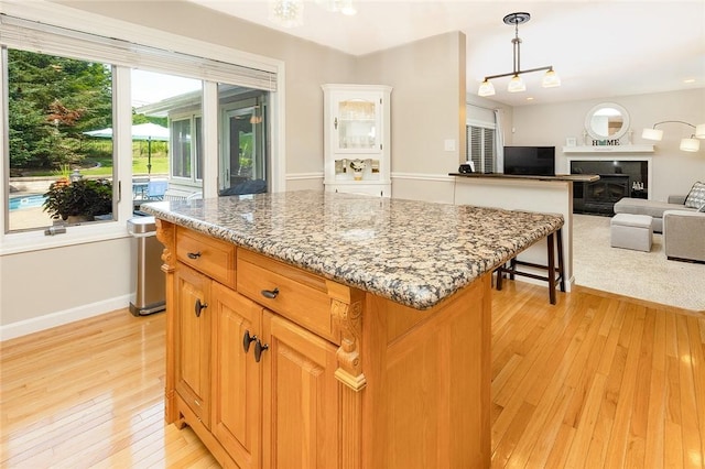 652 Cheyenne Trl, Jackson Twp, PA 16137 - kitchen featuring light wood-style flooring, light stone countertops, a kitchen island, decorative light fixtures, and open floor plan