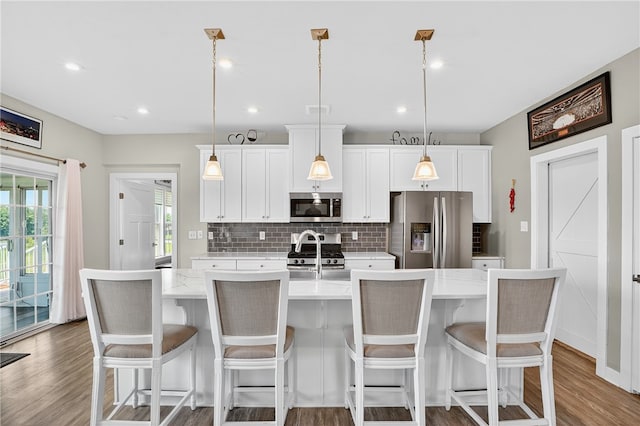 106 High Pointe Dr, Chartiers, PA 15301 - kitchen with stainless steel appliances, wood finished floors, tasteful backsplash, a center island with sink, and white cabinets