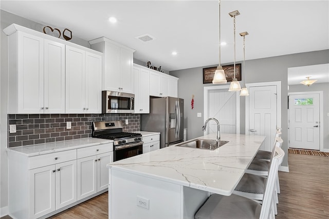 106 High Pointe Dr, Chartiers, PA 15301 - kitchen with stainless steel appliances, tasteful backsplash, light wood-style floors, a center island with sink, and white cabinetry