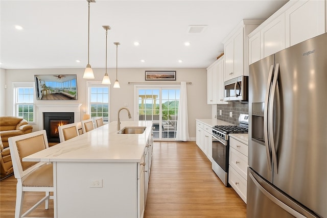 106 High Pointe Dr, Chartiers, PA 15301 - kitchen with stainless steel appliances, a kitchen bar, a kitchen island with sink, light wood-style flooring, and a lit fireplace