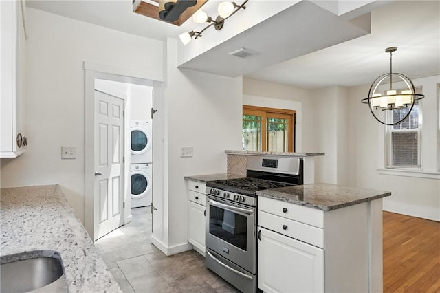 5248 Beelermont Pl, Squirrel Hill, PA 15217 - kitchen with stainless steel range with gas stovetop, stacked washing machine and dryer, white cabinetry, a chandelier, and light stone countertops
