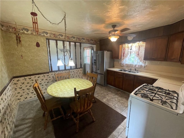 33 Orchard Ln, Carroll Twp, PA 15063 - kitchen with white gas range oven, stainless steel refrigerator with ice dispenser, wallpapered walls, a ceiling fan, and light countertops