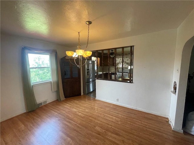 33 Orchard Ln, Carroll Twp, PA 15063 - unfurnished dining area with a chandelier, wood finished floors, arched walkways, and a textured ceiling