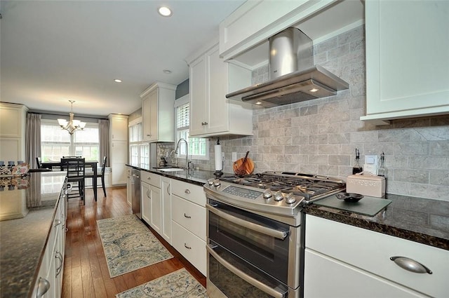 79 W Manilla Ave, Green Tree, PA 15220 - kitchen with stainless steel appliances, wall chimney exhaust hood, a chandelier, dark wood-type flooring, and decorative backsplash