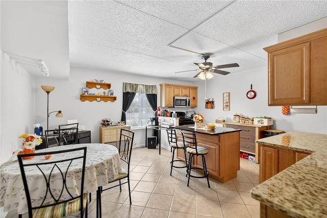 2120 Greentree Rd Unit 610E, Pittsburgh, PA 15220 - kitchen featuring stainless steel microwave, stove, a kitchen island, a ceiling fan, and light tile patterned flooring