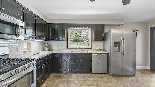 900 N Whitmore Rd, North Huntingdon, PA 15642 - kitchen featuring stainless steel appliances, backsplash, dark cabinetry, and light stone counters
