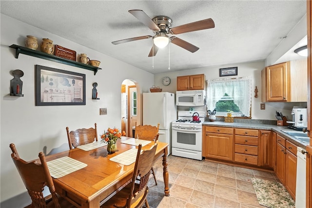 231 E N St, Mercer Boro, PA 16137 - kitchen with white appliances, arched walkways, ceiling fan, dark countertops, and brown cabinets
