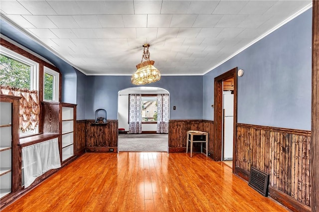 200 38th St, Beaver Falls, PA 15010 - unfurnished dining area with hardwood / wood-style flooring, a wainscoted wall, wooden walls, arched walkways, and ornamental molding