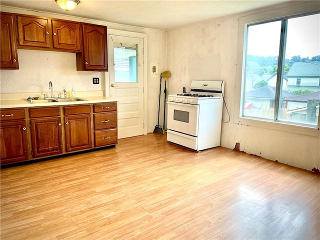 1017 Johnston Ave, Kittanning Boro, PA 16201 - kitchen with white gas stove, light wood-type flooring, light countertops, and brown cabinets