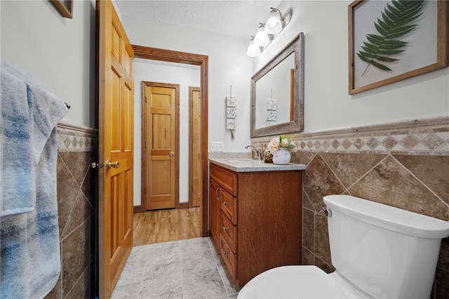 1419 Bullion Rd, Victory Twp, PA 16342 - half bathroom with tile walls, vanity, wainscoting, and a textured ceiling