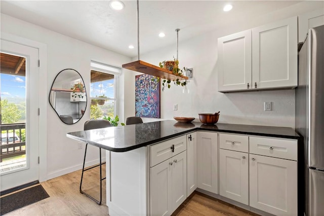 2212 Freeport Rd, Harmar, PA 15238 - kitchen with a peninsula, light wood-style floors, freestanding refrigerator, a kitchen bar, and recessed lighting