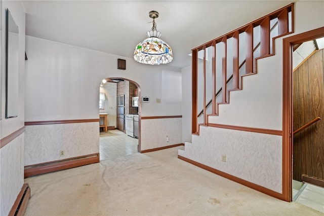 4614 Carroll St, Bloomfield, PA 15224 - unfurnished dining area with arched walkways, carpet flooring, a baseboard heating unit, a wainscoted wall, and stairs