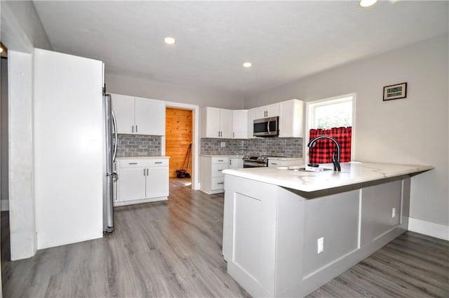 315 Ohio St, Rostraver, PA 15012 - kitchen with a peninsula, decorative backsplash, white cabinets, light countertops, and appliances with stainless steel finishes