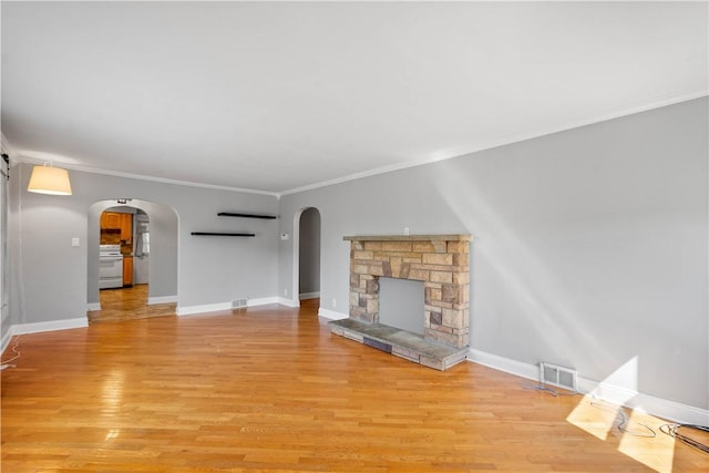 57 Welcome St, East Bethlehem, PA 15333 - unfurnished living room with ornamental molding, light wood-style flooring, arched walkways, and a stone fireplace