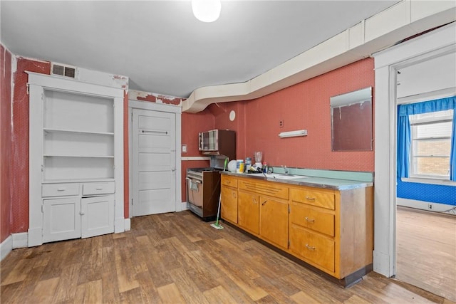 827 Beaver Rd, Ambridge, PA 15003 - kitchen with wood finished floors, stove, stainless steel microwave, light countertops, and brown cabinets