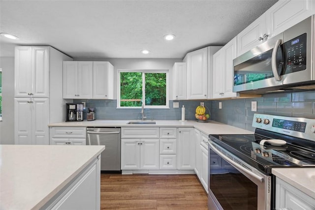215 E Edgewood Dr, Peters Twp, PA 15317 - kitchen with appliances with stainless steel finishes, light countertops, white cabinetry, wood finished floors, and recessed lighting