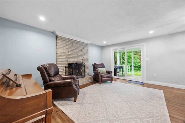 215 E Edgewood Dr, Peters Twp, PA 15317 - living room featuring a stone fireplace, wood finished floors, a textured ceiling, and recessed lighting