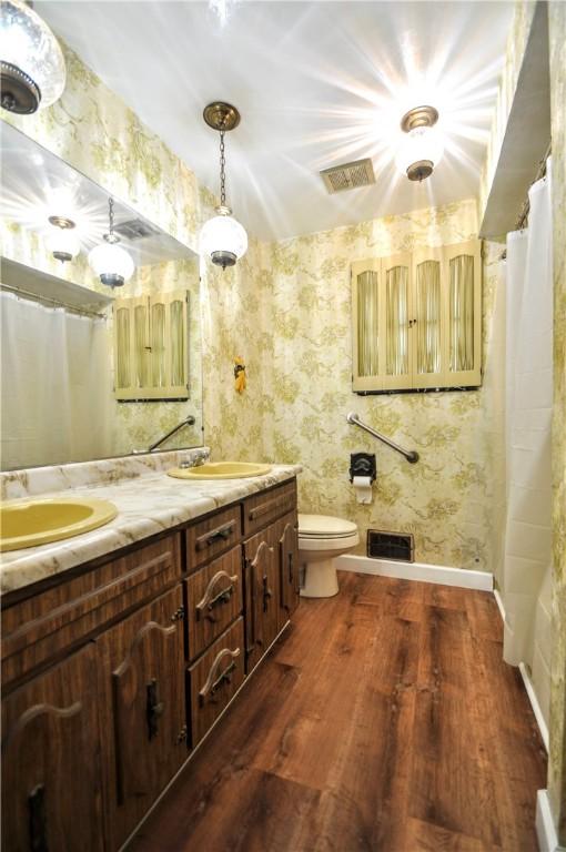 306 Barbara Dr, Carroll Twp, PA 15063 - bathroom featuring wood finished floors, double vanity, wallpapered walls, and curtained shower